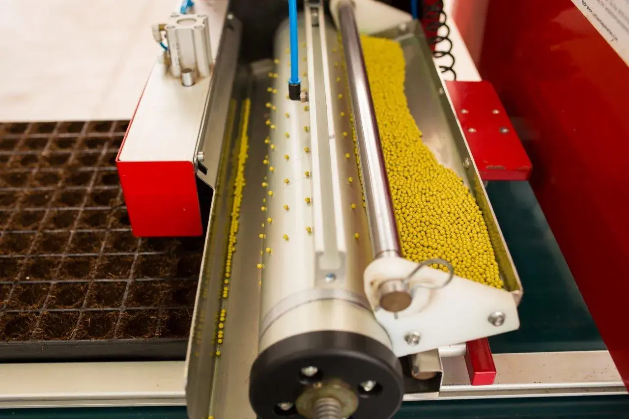 Máquina de semeadura distribuindo sementes nas bandejas